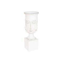 Tall white urn-shaped planter with faces in relief around the bowl, standing on a square white plinth