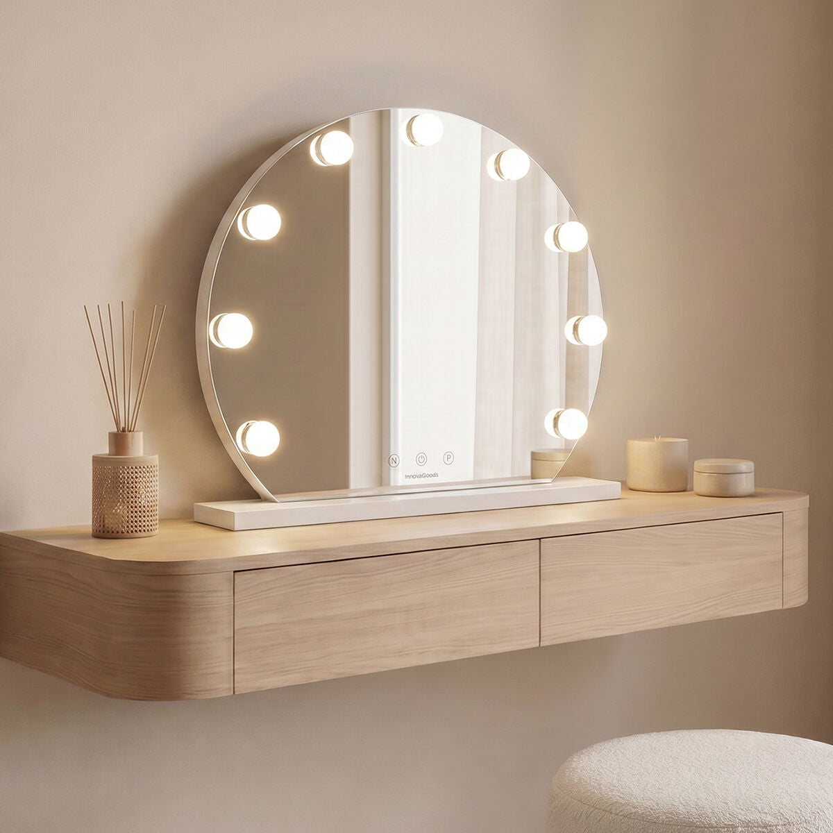Round white LED vanity mirror with nine bulbs standing on a dressing console beside a reed diffuser
